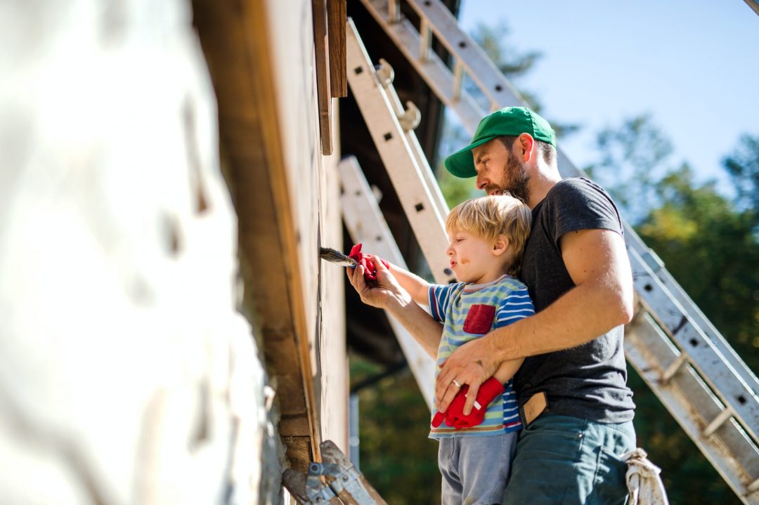 a-father-and-toddler-boy-outdoors-in-summer-painting-wooden-house-.jpg